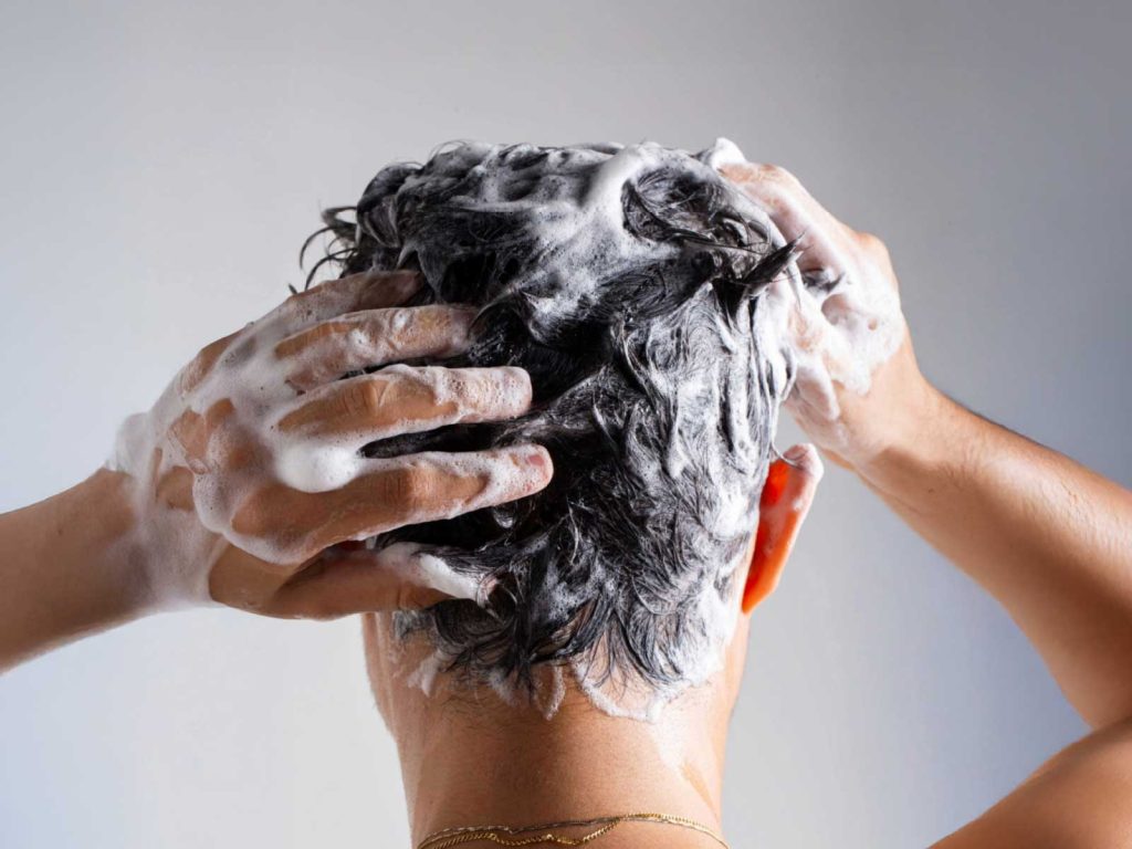 Pessoa lavando cabelo com shampoo