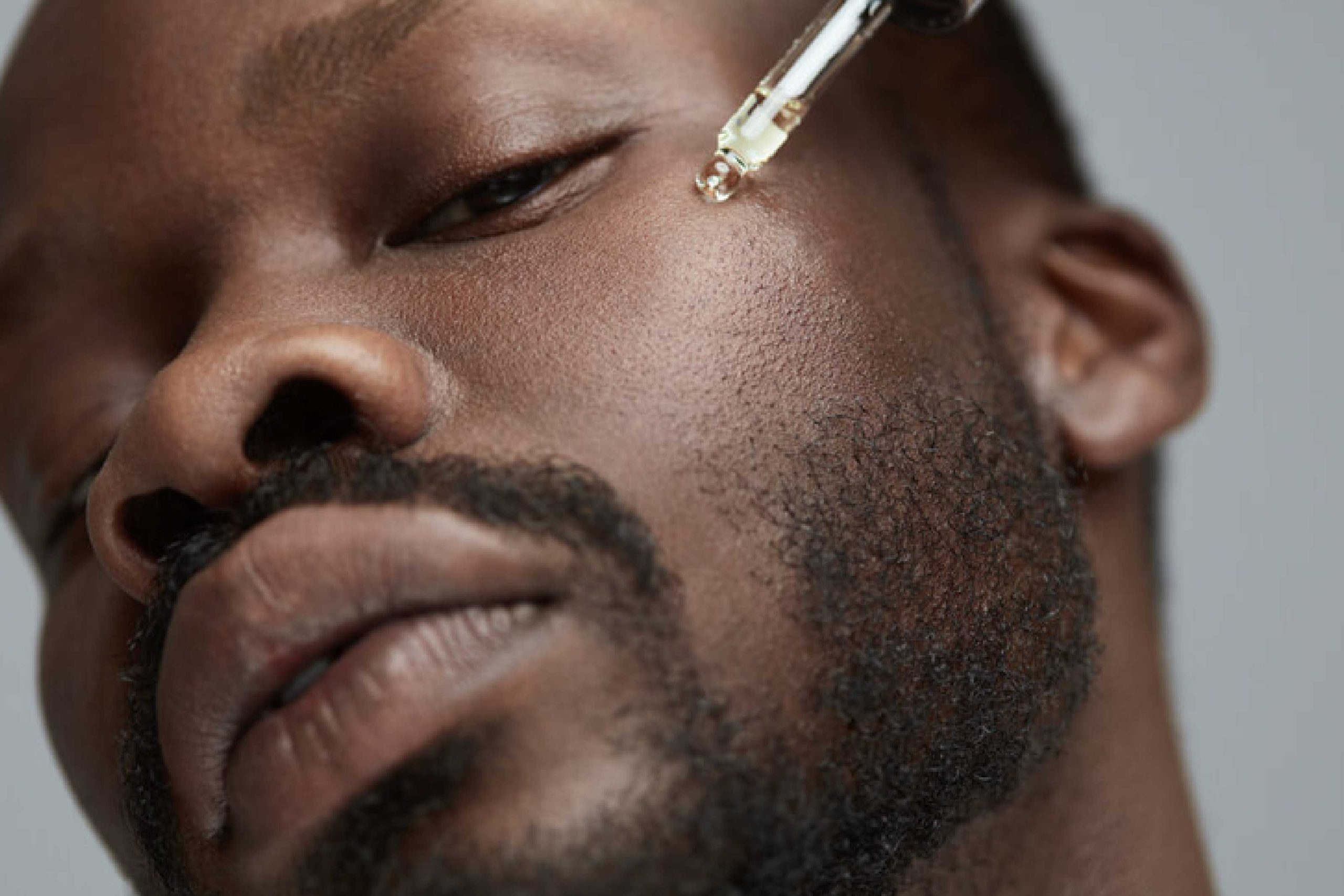 Homem aplicando óleo facial em sua pele