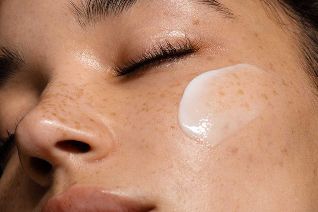 Aplicação de creme facial sobre pele com sardas